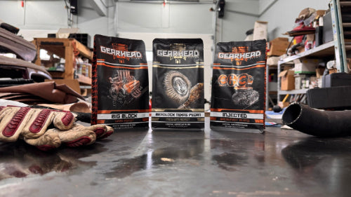 Three 'Gearhead' product packages on a workbench in a garage setting.